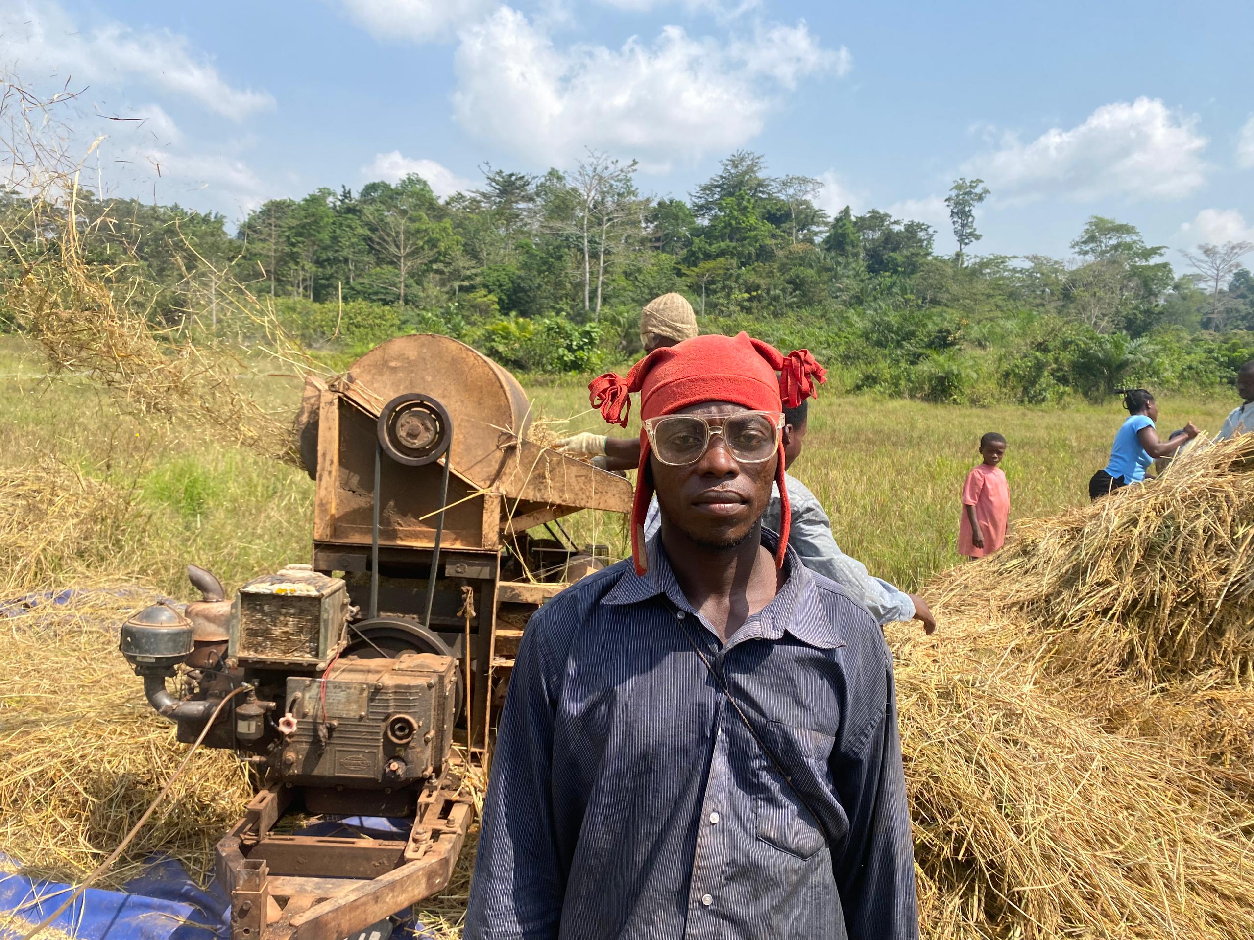 worker in front of rice and thresher